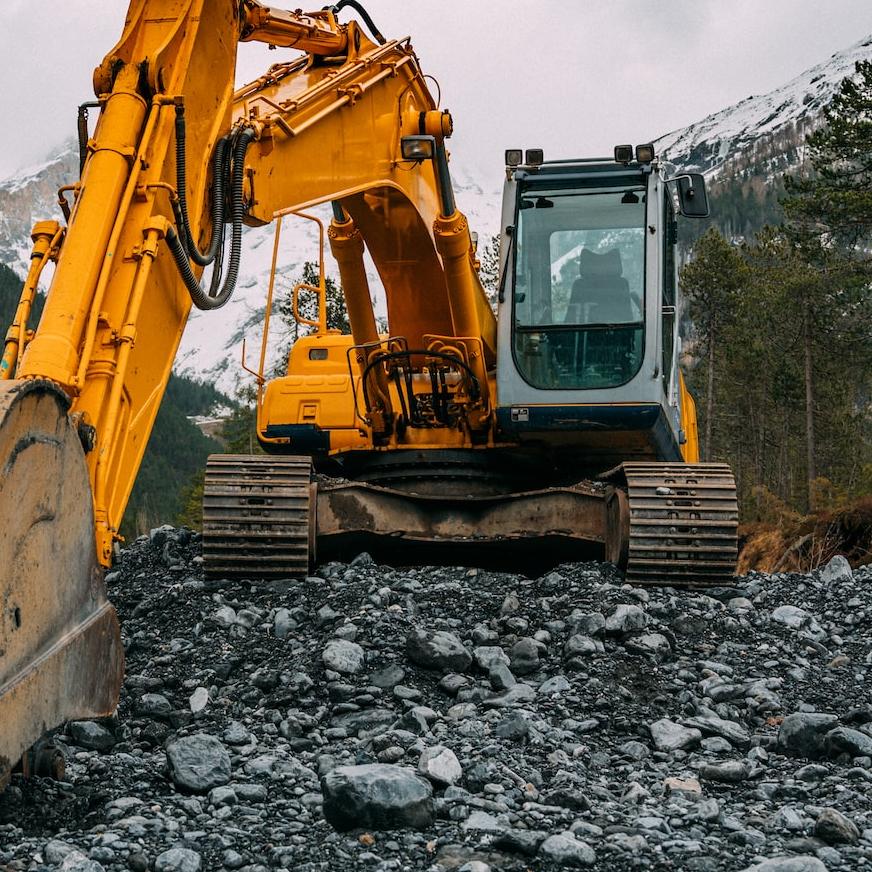 yellow and black excavator on rocky ground