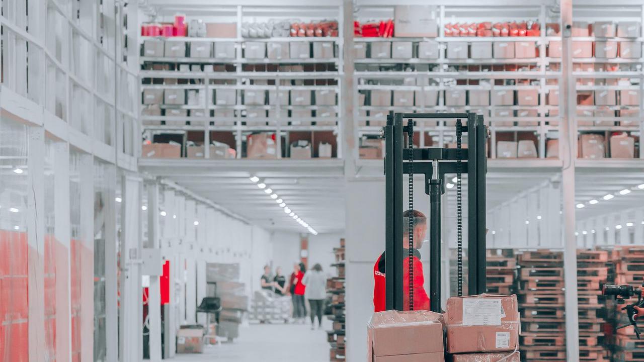 man in black pants and black jacket standing on black and red fork lift