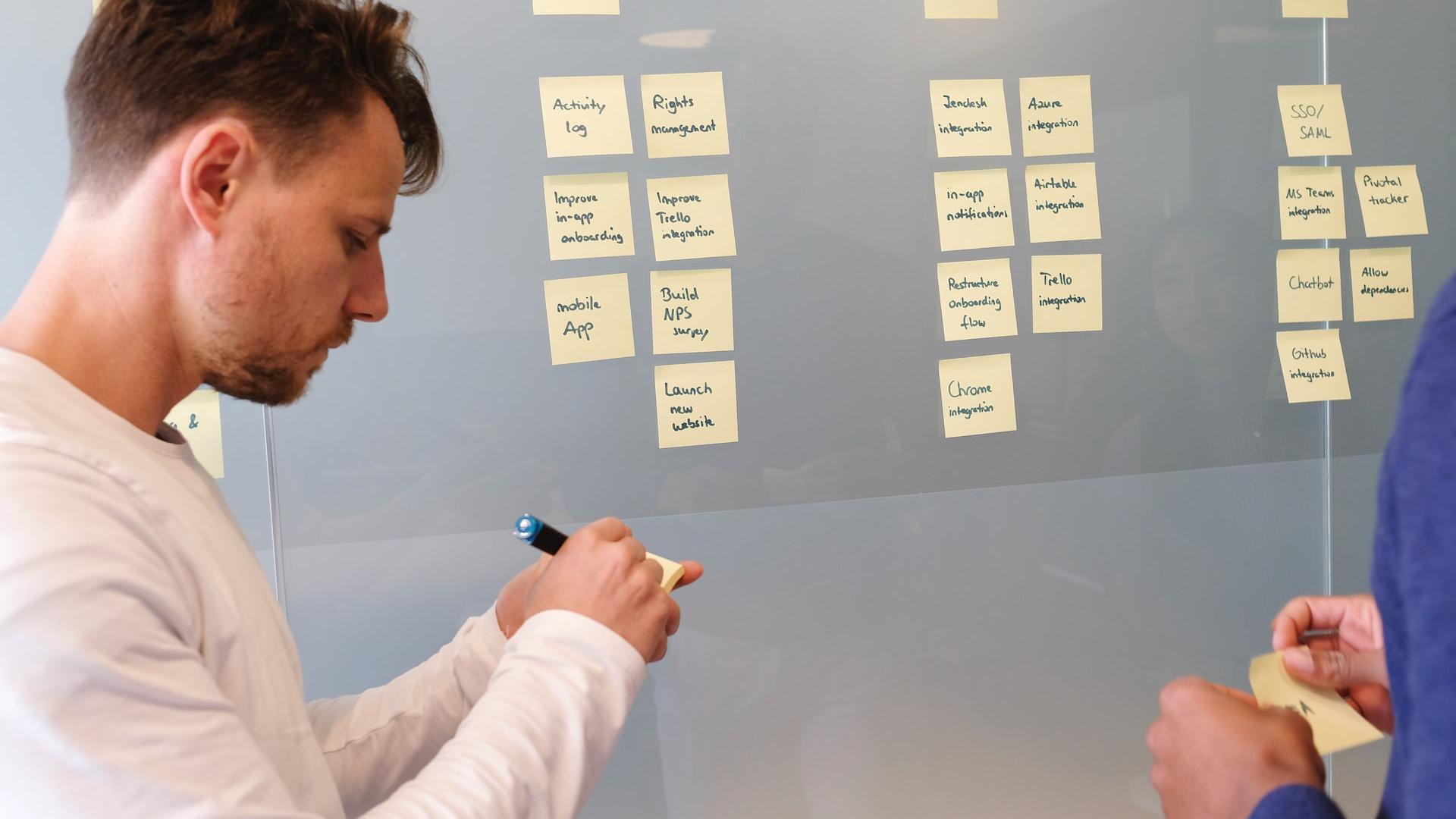 man in white long sleeve shirt writing on white board